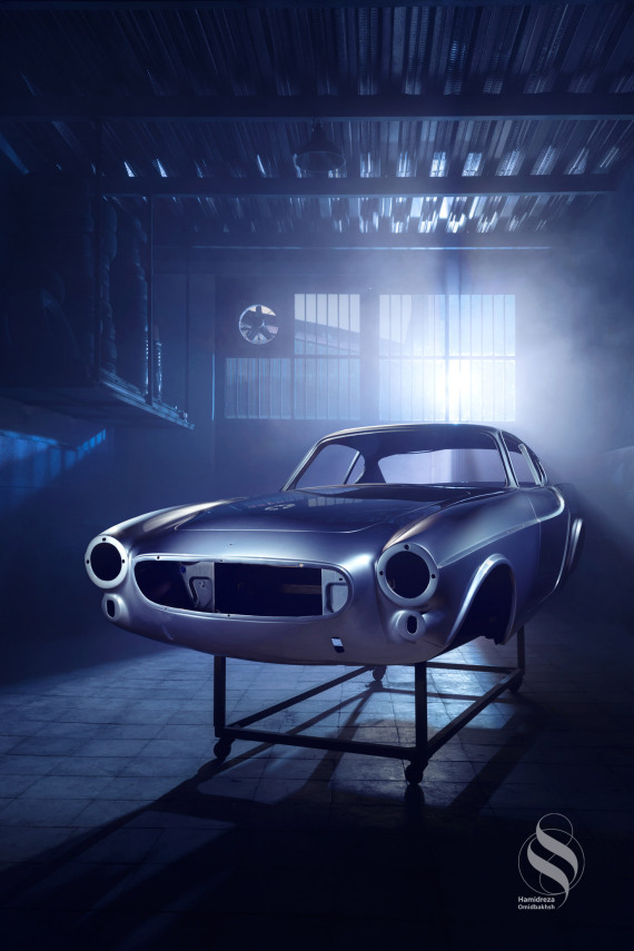 Automotive Photography of Volvo P1800/1800 in restoration shop. Photographed by Hamidreza Omidbakhsh with improvised lighting design. When we arrived to photograph the Volvo body in its early stages of restoration, I felt a deep sense of concern. How could we capture the essence of this empty body, which lacked inherent attractiveness for photography? Moreover, the unappealing environment posed an additional challenge. Nonetheless, I realized that the only solution was to create an improvised lighting design to overcome the limitations imposed by the surrounding space. I carefully selected a neglected corner in the restoration shop, where a suitable light maneuver could be executed. With the assistance of my team, we implemented the lighting design, and the outcome exceeded our expectations.​​​​​​​